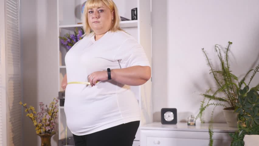 fat woman measures the waist and is sad