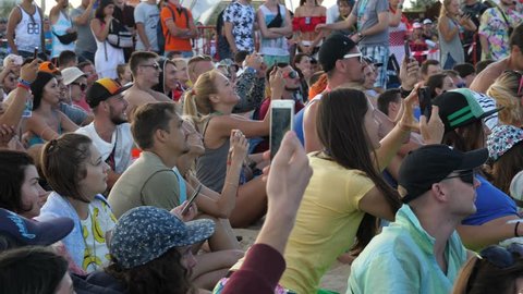 ZATOKA near ODESA, UKRAINE - AUG 24, 2017: Young People Crowd Sit By Stage Raise Mobile Phones Over Heads Shoot Video Of Public Concert Performance