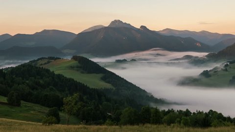 Sunbeams moving over foggy mountain valley at sunrise. Mist morning in beautiful rural landscape time lapse
