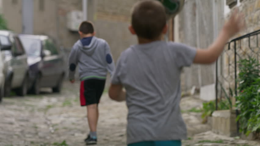 Medium slow motion panning shot of children playing street soccer / Veliko Tarnovo, Bulgaria