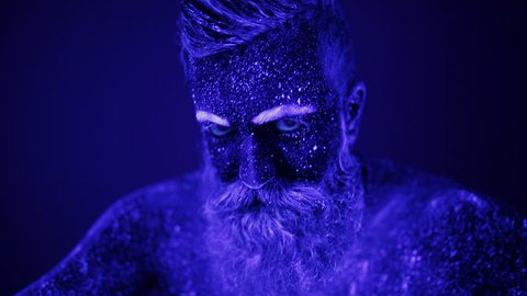 An evil man with a beard in the ultraviolet light is frighteningly screaming