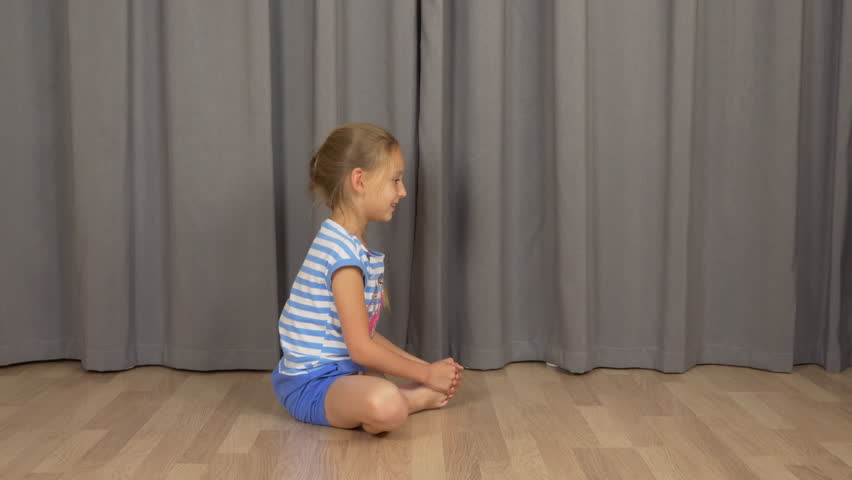 Young girl do yoga butterfly pose. White girl stretchin at living room indoors.