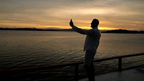 Man holding smartphone and recording the view during sunset, slow motion shot at 240fps, steadycam shot 
