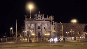 Video of a city life or Rome, Italy. People are walking and the cars pass through a beautiful square in Rome at night.