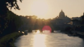 Blurred video of a wonderful view of a sunset that is coming down behind the great St. Peter's Basilica in Rome, Italy. Video shot from a bridge over the Tiber river. (defocused) 