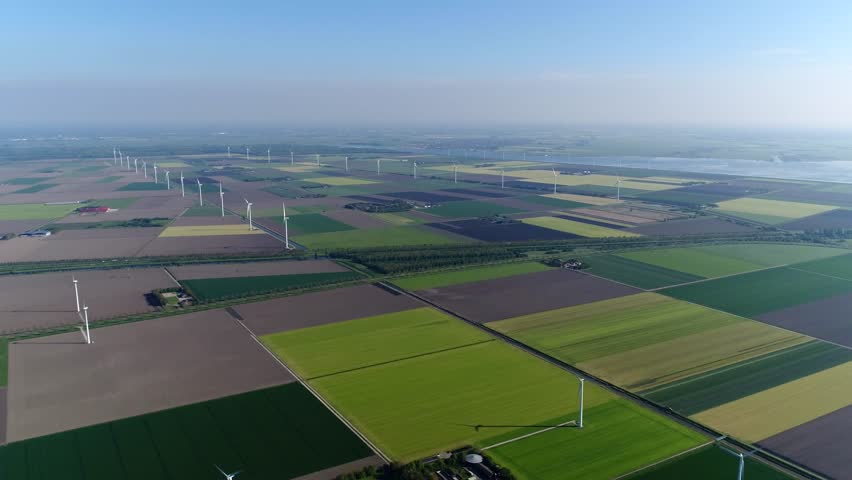 Bird view aerial of polder landscape showing different colors of the farm land and also showing wind turbines providing renewable energy from wind typical dutch flat land far horizon 4k quality Royalty-Free Stock Footage #31224664