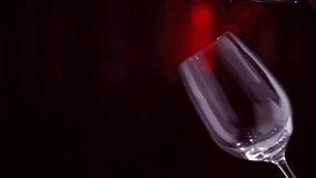 Wine. Red wine pouring in wine glass over dark background. Border design. Slow motion 4K UHD video 3840x2160