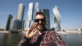 Happy tourist man having online video chat using his smartphone camera near international business center in Moscow