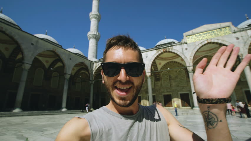 Handheld of Happy tourist man having online video chat using his smartphone camera near famous blue mosque in Istanbul