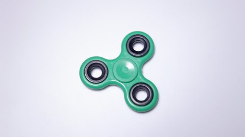 A slowly rotating fidget spinner toy. Close-up above shot.

