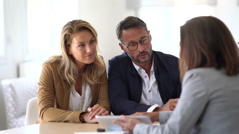 Mature couple meeting real-estate agent in office