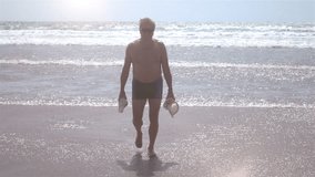 High quality video of lovely senior man walking from the ocean with shells in real 1080p slow motion 250fps