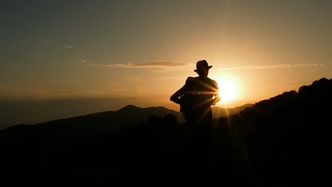 Male Mountain Climber In Summer. Man Hiking in Mountains Enjoying Success. Hiking Walking Slow Motion Recreation Activity. Holiday Vacation Tourism, Outdoors Man Hiking Silhouette  Beautiful Sunset.