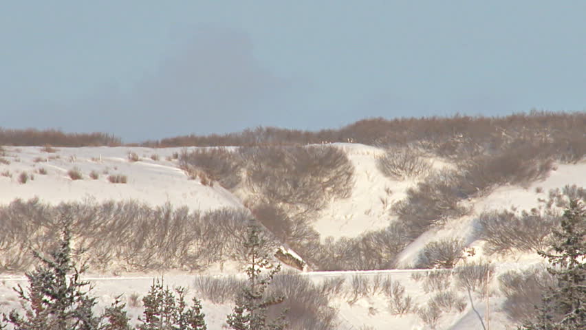 Long shot of SUV driving right to left on snowy road in Alaska.