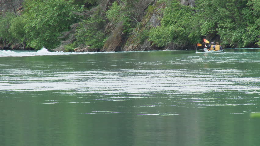 Two women in a tandem kayak choose their route and run the rapids in a green