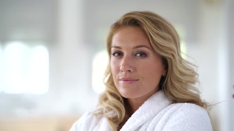 Portrait of beautiful 40-year-old woman relaxing in bathrobe at home