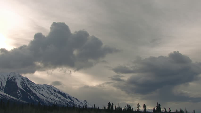 Cloud monster in the sky over dark mountains in Yukon Territory, Canada - time