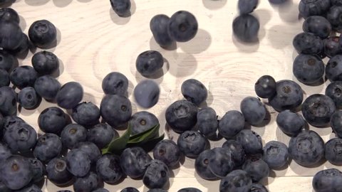 Blueberry berry. Berries of blueberries fall on a wooden table. Slow motion 240 fps. High speed camera shot. Full HD 1080p. 