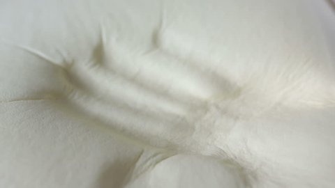 Slow motion of an hand while it is touching and pressing a memory foam sponge technology mattress and pillow of a modern bed.
