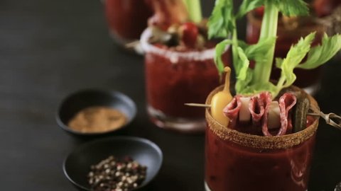 Bloody mary cocktail garnished with celery sticks, olives, and bacon strips.