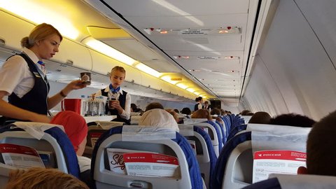 ROSSIYA AIRLINES FLIGHT, RUSSIA - CIRCA SEP 2017: Interior of airplane economy class cabin with passengers on seats. Flight attendants serves food and drinks to passengers on a Boeing 737-800.