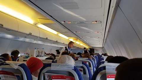 ROSSIYA AIRLINES FLIGHT, RUSSIA - CIRCA SEP 2017: Interior of airplane economy class cabin with passengers on seats. Flight attendants serves food and drinks to passengers on a Boeing 737-800.