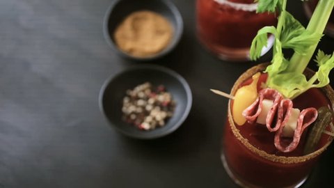 Bloody mary cocktail garnished with celery sticks, olives, and bacon strips.