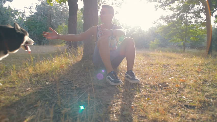 young caucasian male playing with siberian husky dog in park