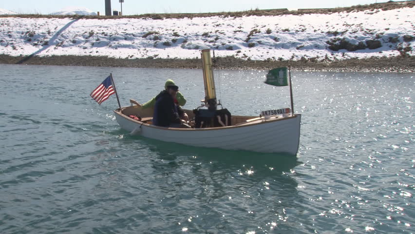 Small antique steam-powered boat maneuvering in harbor waters.