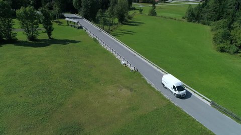 Aerial - High angle view of delivery van driving and transporting cargo on a road through the countryside