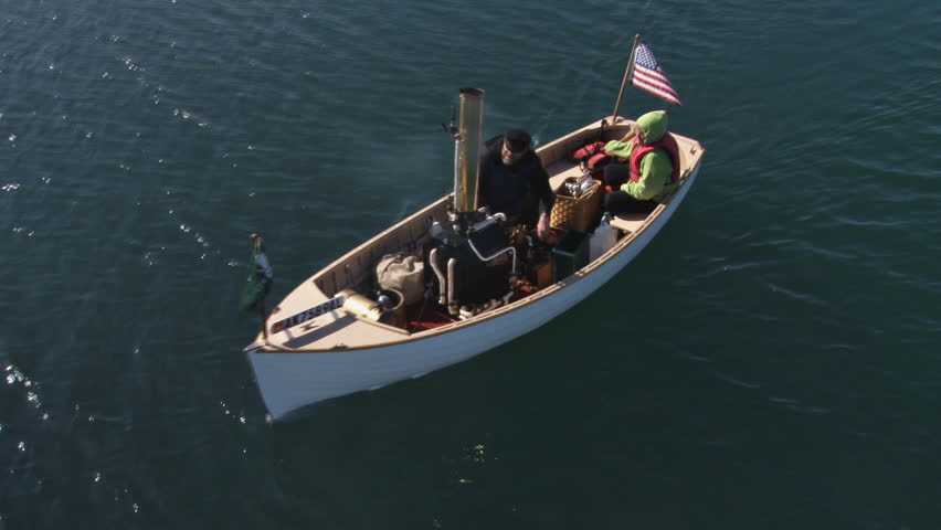 Small antique steam-powered boat maneuvering in harbor waters.