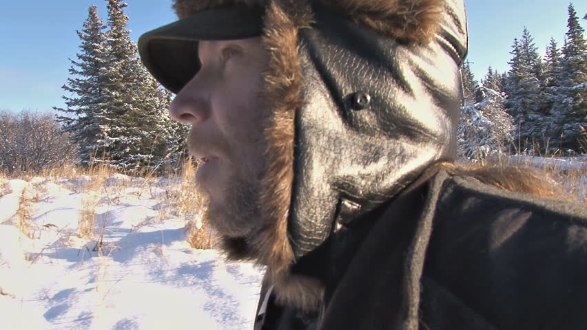 Suited up for the cold, a man walks through snowy country. Alaska that is. With