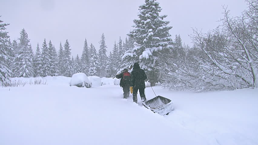 A man and woman in snowshoes and heavy winter garb arrive at the parking area by