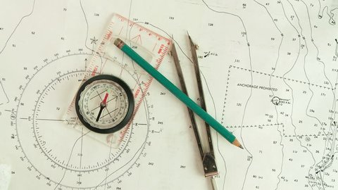 Male hands using compass & nautical charts to navigate, POV