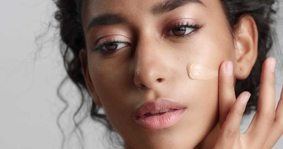 Young woman with beautiful olive skin applying liquid foundation or BB cream to her cheeks isolated on white | Shutterstock HD Video #31295515