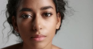 Close up video of an attractive young model with light brown skin and long black hair curling her eyelashes