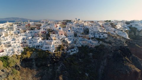 Aerial view of iconic white houses and blue dome churches on steep cliff, Santorini Island, Greece. Village of Oia. Morning light