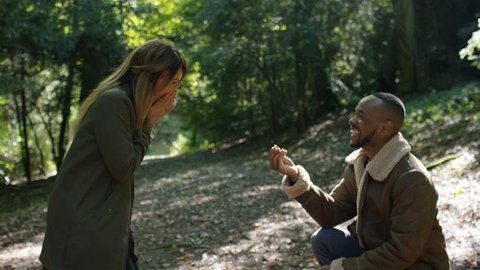 Young couple in the woods walk before the man makes a marriage proposal