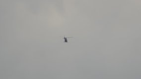 Helicopter far away in air in the gray sky.
