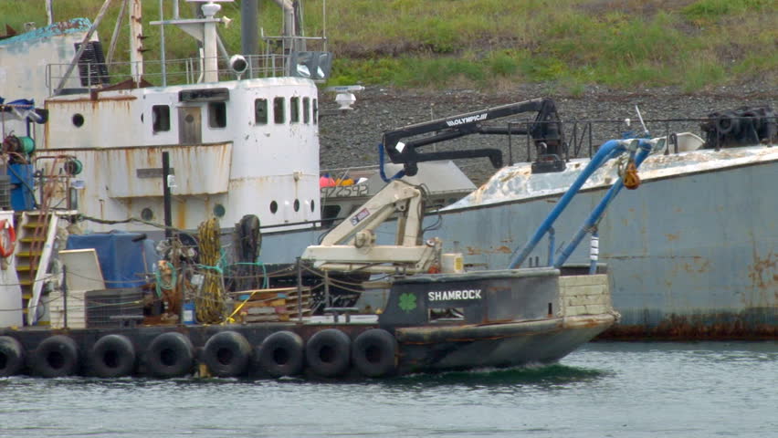 KACHEMAK, AK - CIRCA 2012: Working boat in harbor moving past other interesting