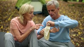 Aged pleasant man apllying bandage on his wife wrist