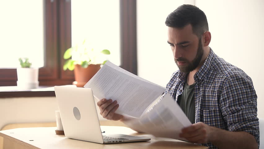 Stressed unmotivated man confused by mistake in documents, looking through papers, frowning using laptop, failing urgent task, missing deadline, quits after bad work fed up with difficult job Royalty-Free Stock Footage #31313923