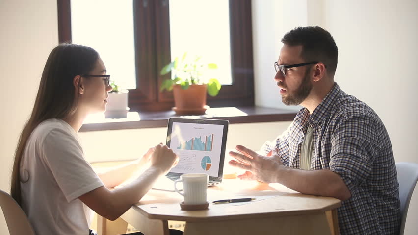 Young man and woman negotiating, colleagues discussing project result with infographic statistics on laptop screen, teamworking at meeting, startup team sharing ideas and brainstorming in office | Shutterstock HD Video #31313938