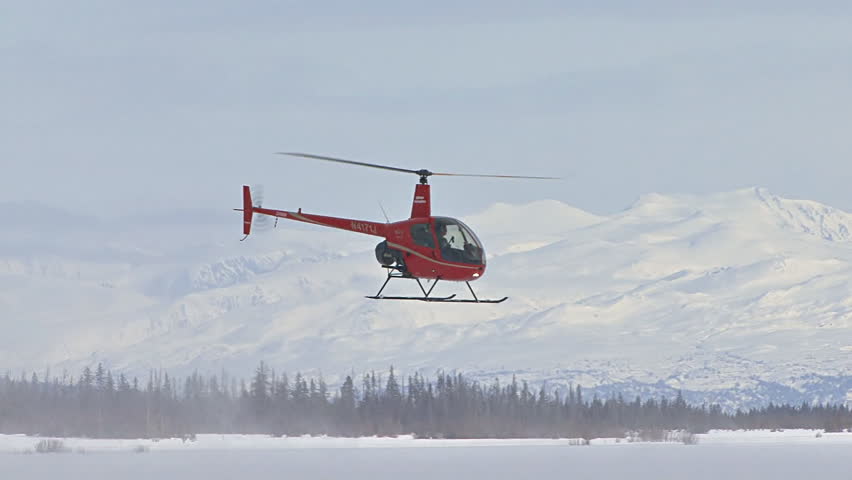 HOMER, AK CIRCA 2012: Red 2-man helicopter (Robinson R22) flies away from frozen