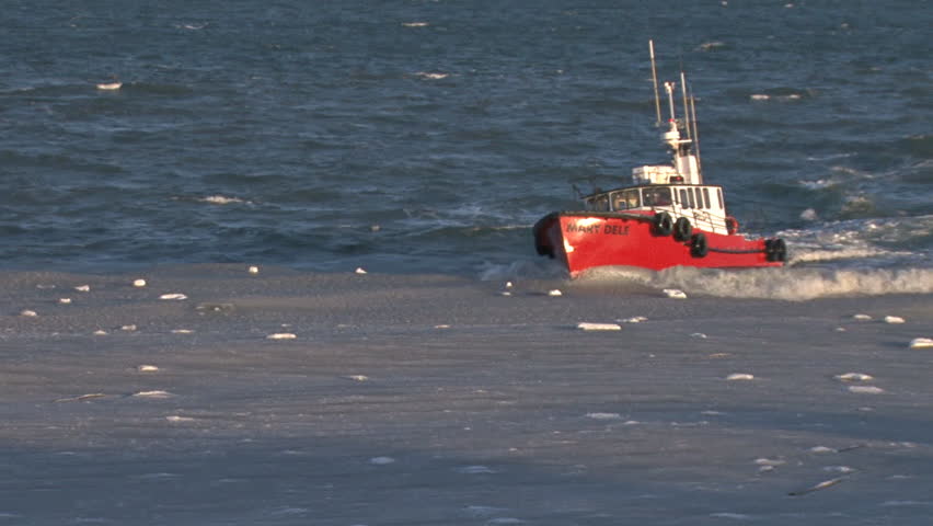 HOMER, AK CIRCA 2012: A red pilot boat returns to Homer Harbor dashes back after