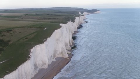 Slow aerial flight with anti-clockwise gentle pan of white chalk cliffs from Seven Sisters to Beachy Head finishing over cliff plateau in the UK