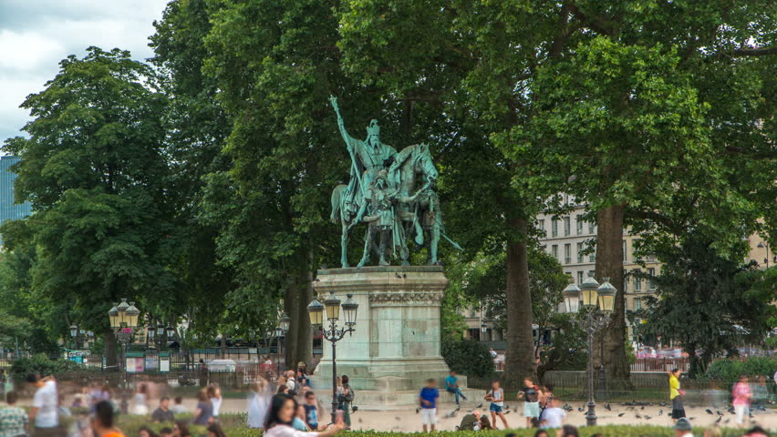 Statue Charlemagne et ses Leudes timelapse by Cathedrale Notre Dame de Paris. People walking and sitting around at summer day. Green trees on background