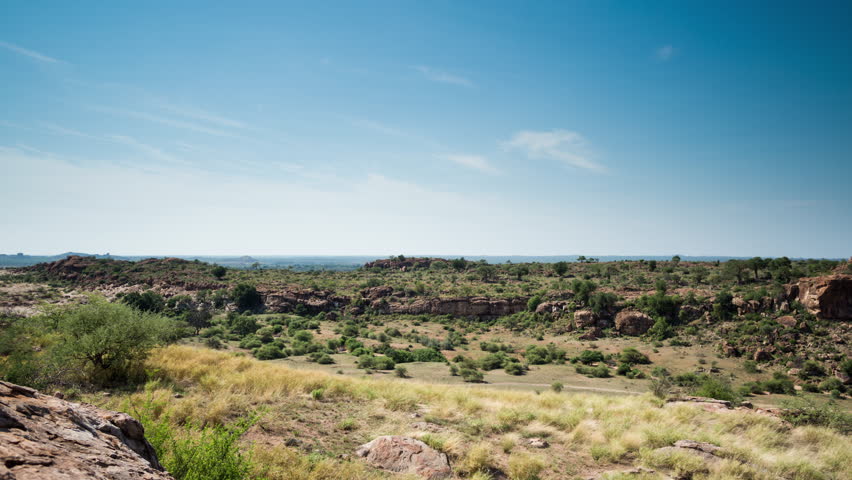 A slow linear moving, full day timelapse of a green rocky landscape, showing stormy clouds gathering and a herd of elephants feeding in the Mashatu Game Reserve, Botswana. 4K
