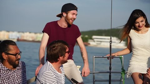 The alumni company celebrates a vacation on a modern boat, classmates communicate on a yacht in the evening, men and women are beautifully dressed and enjoy the evening sunset in the summer