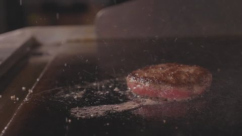 Chef cooking juicy meat cutlet for the burger and cleaning electric commercial stove. Junk street food, bistro kitchen slow motion 180 FPS